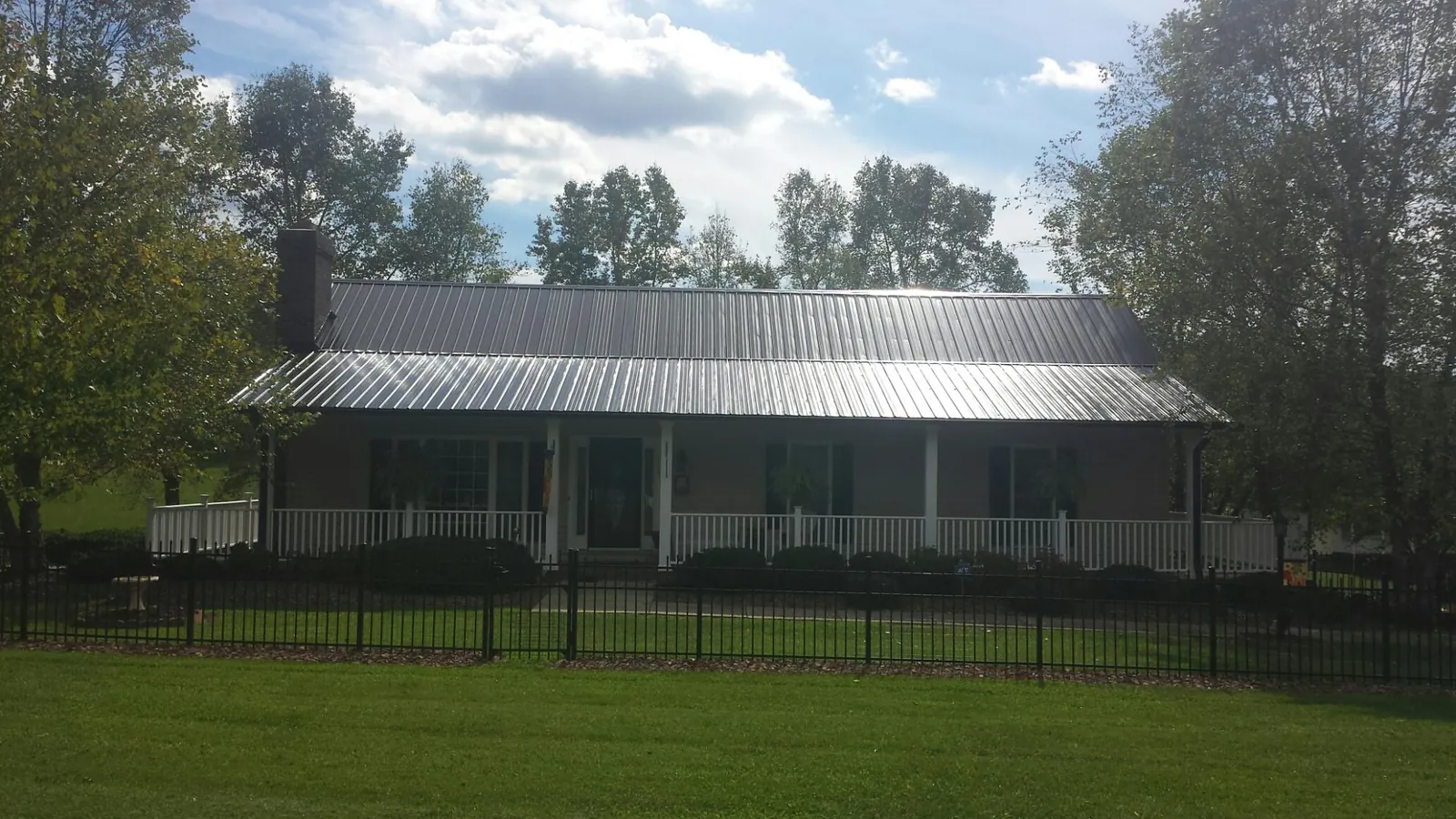 Gray metal roof on a brick ranch with a full width front porch — Gutter Guard Installation work by our crew in Aspen